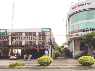 Sau khi nắn đường, đất của Chủ tịch Đấu ở bên phải đã được xây lên tòa nhà cho thuê và phía sau còn hai tòa nhà khác. Còn đất của bà Khoa bên trái, nhà cửa được thông báo di dời để làm đường giai đoạn hai. Ảnh: Sáu Nghệ. Sau khi nắn đường, đất của Chủ tịch Đấu ở bên phải đã được xây lên tòa nhà cho thuê và phía sau còn hai tòa nhà khác. Còn đất của bà Khoa bên trái, nhà cửa được thông báo di dời để làm đường giai đoạn hai Ảnh: Sáu Nghệ