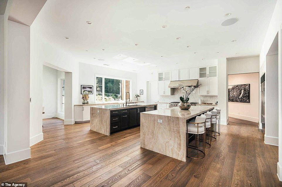 Phòng bếp siêu rộng, với sàn gỗ, ở giữa có chỗ rửa và bàn với bề mặt là đá granit. Phòng bếp siêu rộng, với sàn gỗ, ở giữa có chỗ rửa và bàn với bề mặt là đá granit.