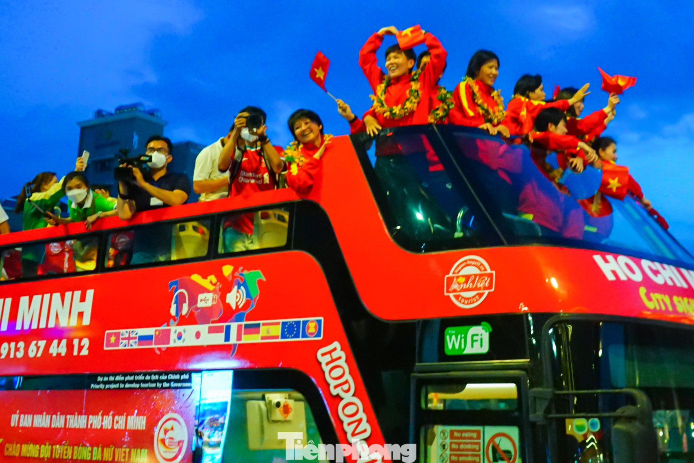 Các cô gái đội tuyển nữ vui mừng thả tim chào các cổ động viên trên đường di chuyển về UBND thành phố