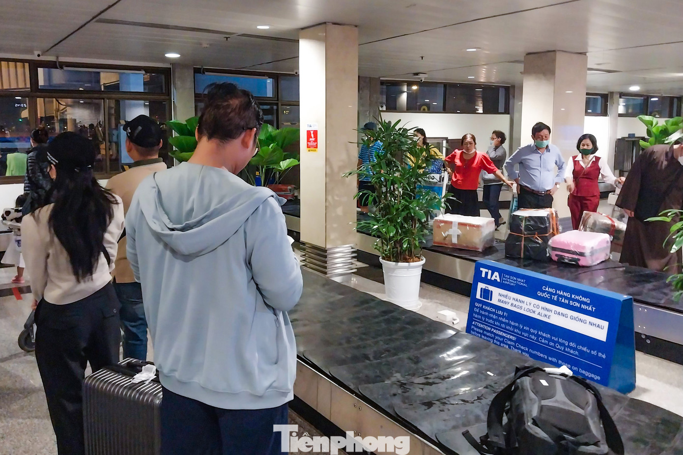 Tại khu vực băng chuyền, hàng trăm hành khách đứng xếp hàng chờ lấy hành lý.