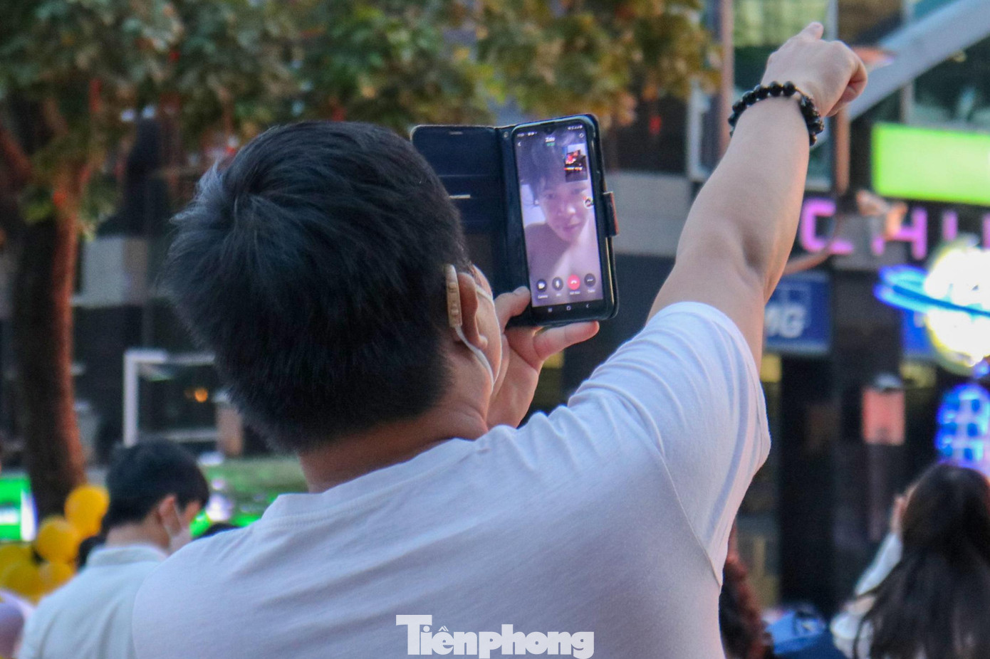 Do bất tiện trong việc di chuyển, người bạn nam thanh niên này phải dùng video call cho bạn mình được hòa chung không khí tại phố đi bộ.