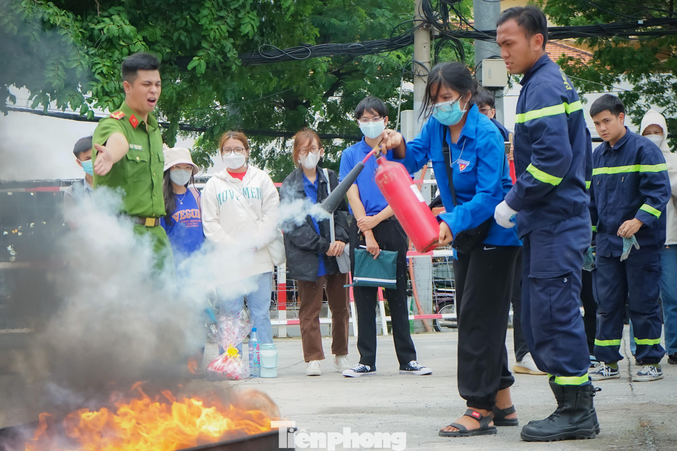 Một nữ chiến sĩ Mùa hè xanh trường ĐH Sài Gòn được các chiến sĩ PCCC hướng dẫn sử dụng bình chữa cháy để dập tắt đám cháy.