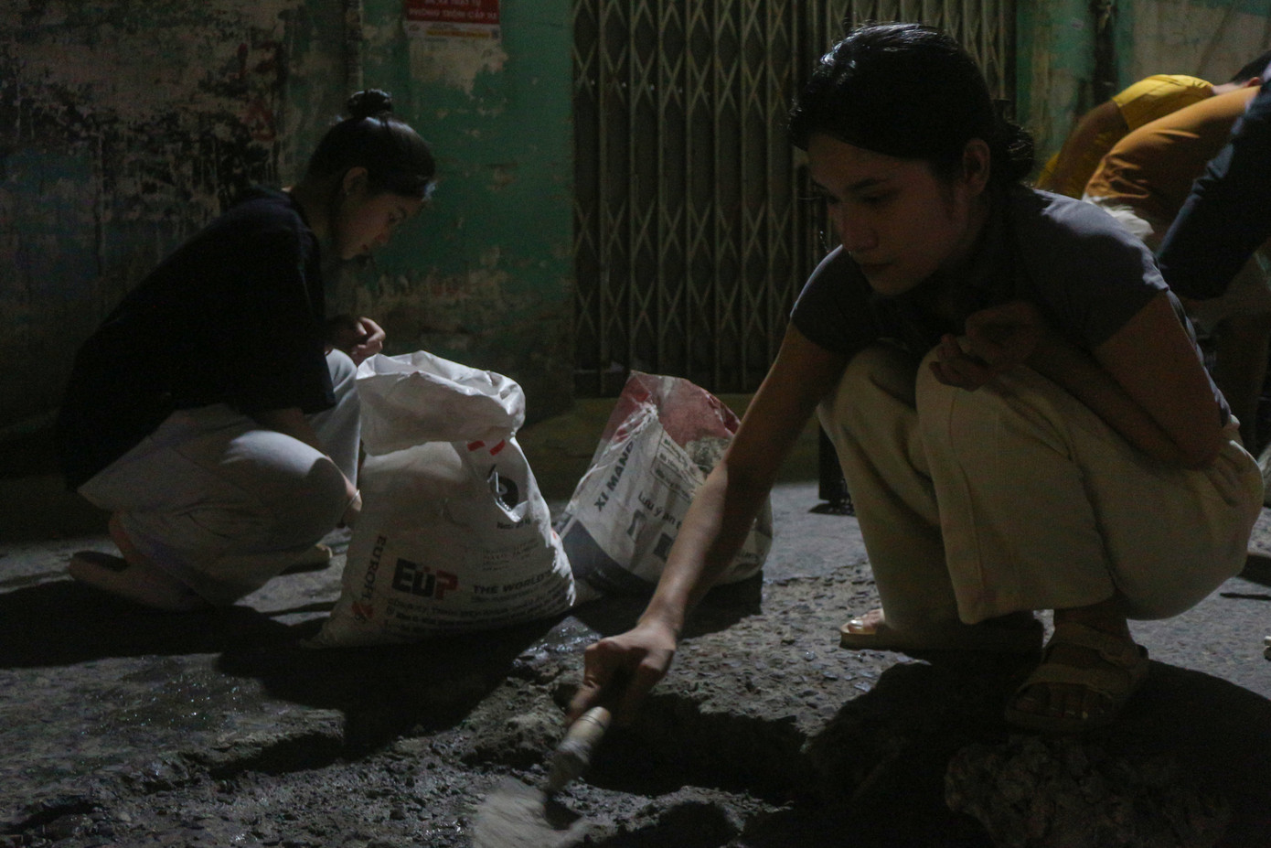 Còn những thành viên nữ sẽ thay phiên nhau cầm bay, trát xi măng vào những phần đường bị hư.