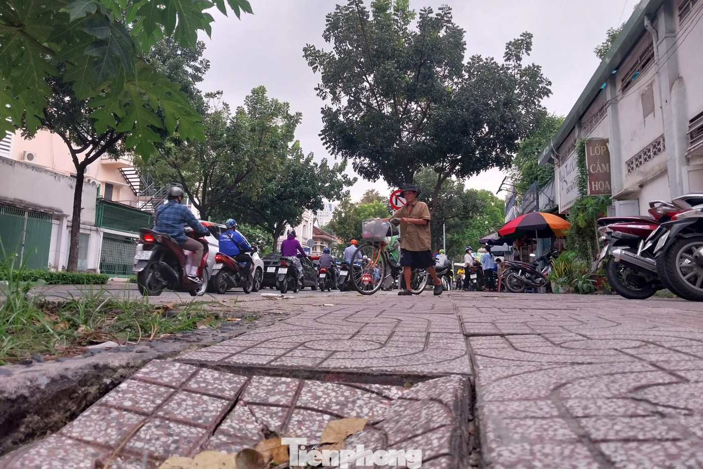 Người bán vé số trên đường Bà Huyện Thanh Quan quyết định đi xuống lòng đường do phần vỉa hè phía trước bị vỡ, sụt lún