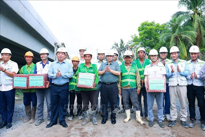 Thủ tướng Phạm Minh Chính tặng quà công nhân thi công cao tốc Cần Thơ - Cà Mau đoạn qua huyện Phụng Hiệp, tỉnh Hậu Giang. Ảnh: Dương Giang/TTXVN
