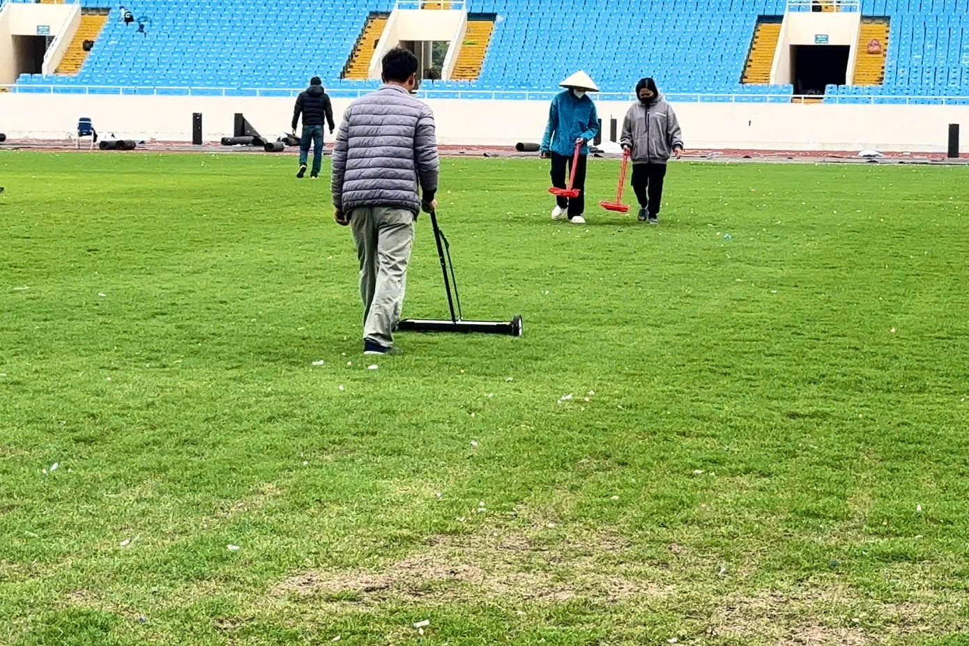 Công nhân thu dọn những vật thể lạ tồn tại trên mặt cỏ sân vận động Mỹ Đình sau hai đêm nhạc.