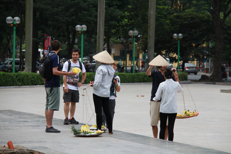 Bị đeo bám mãi, một người khách nước ngoài nhận lấy quang gánh để lên vai, sau đó rất nhanh trả lại người bán hàng rong. Ảnh: Trường Phong