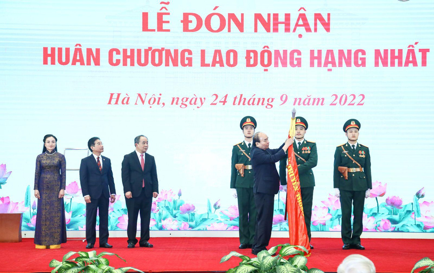 Chủ tịch nước Nguyễn Xuân Phúc gắn Huân chương Lao động hạng Nhất lên lá cờ truyền thống của Văn phòng Chủ tịch nước. Ảnh: VPCTN