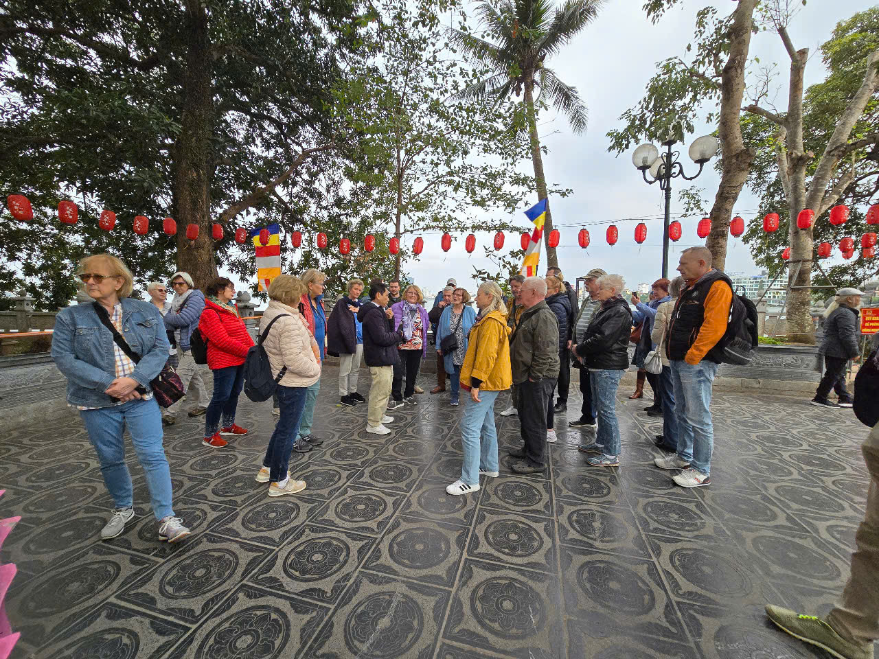 Một đoàn du khách quốc tế đang nghe hướng dẫn viên thuyết minh tại chùa Trấn Quốc.