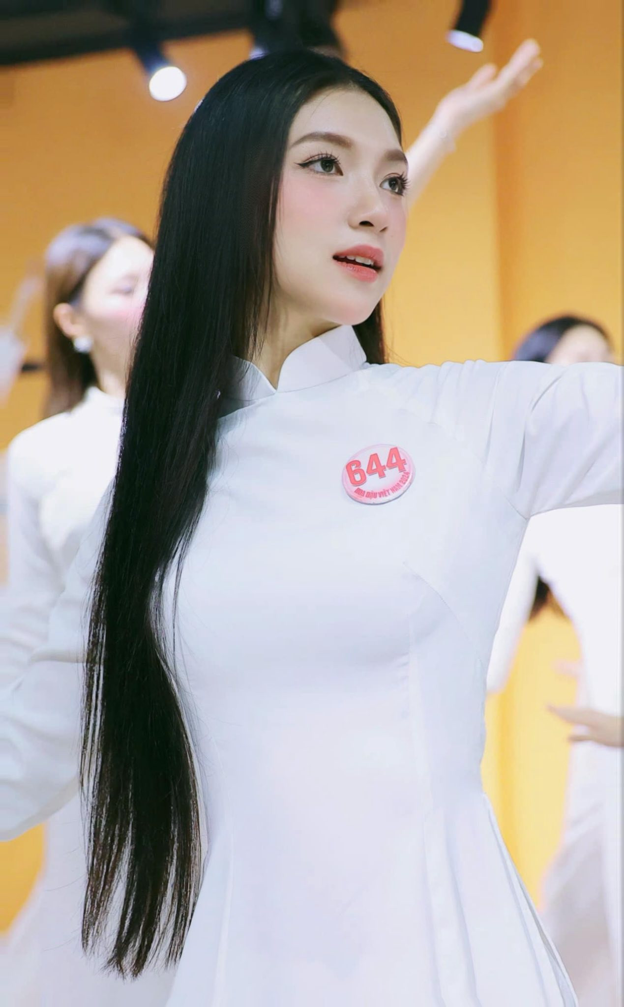 Vũ Yến khoe nhan sắc trong trẻo, dịu dàng với tà áo dài trắng trong buổi học múa trước thềm sơ khảo. Cô có gương mặt bầu bĩnh, mái tóc đen dài, thẳng tự nhiên.