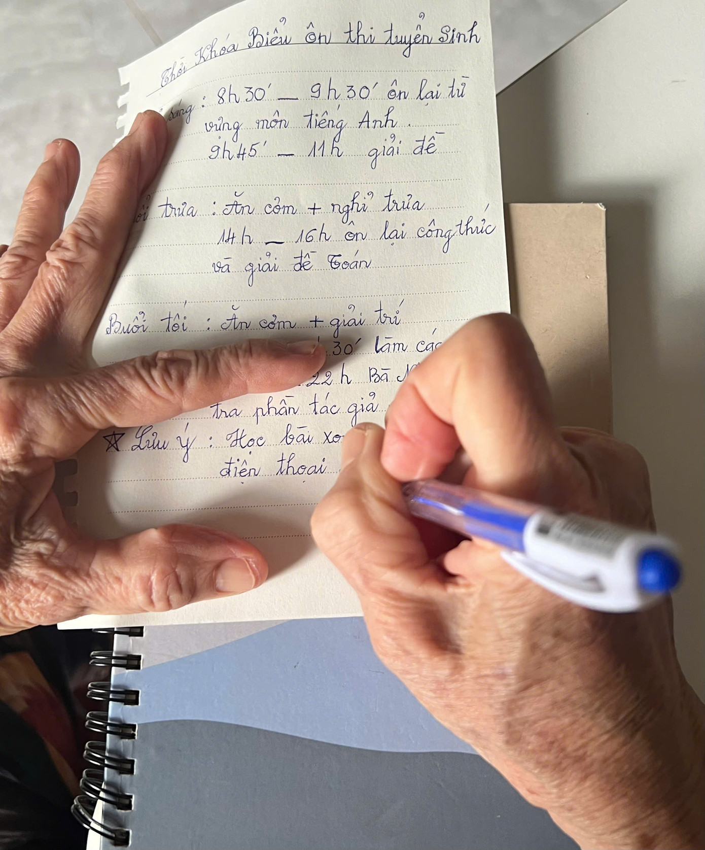 Bà Hồng nắn nót từng nét chữ rất tỉ mỉ viết thời khóa biểu cho cháu. Ảnh: Phương Anh