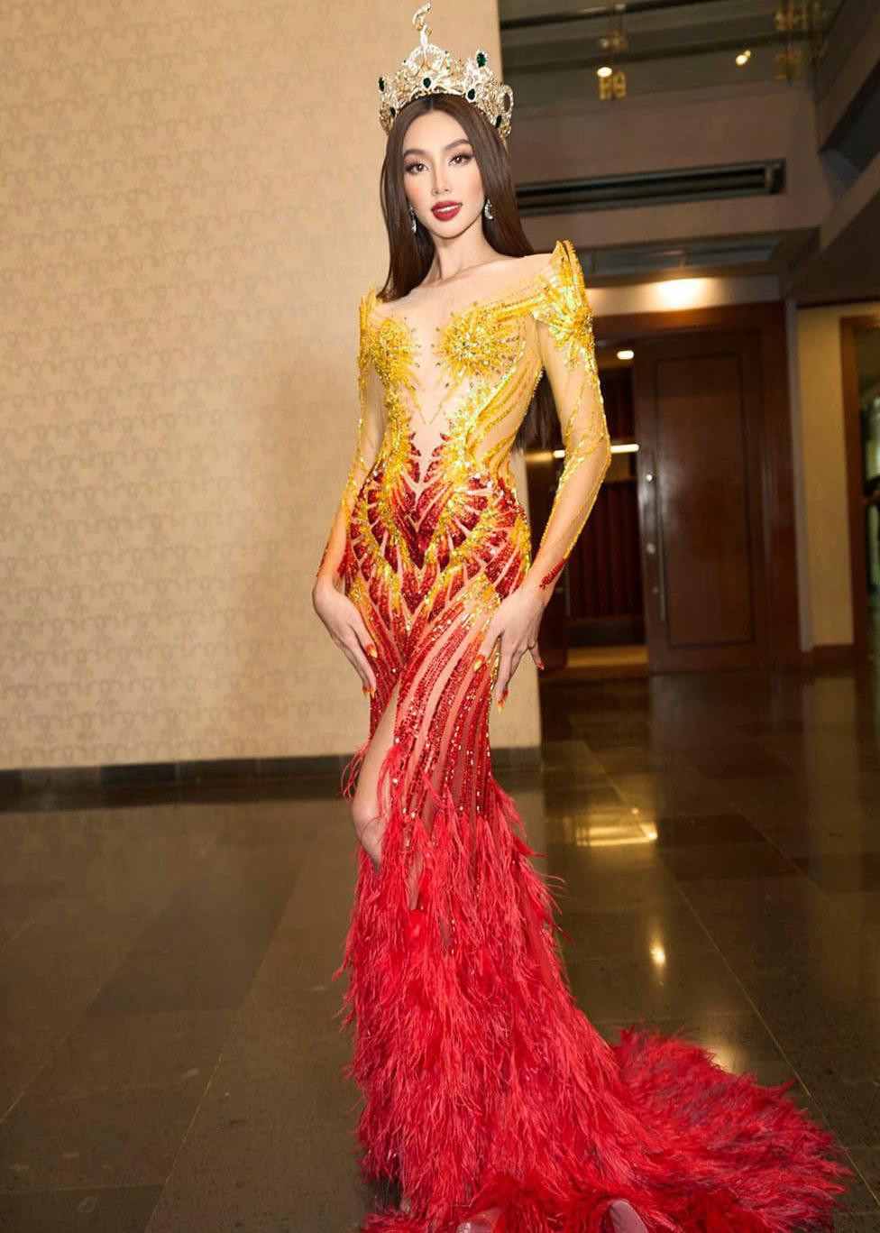 Trong màn xuất hiện trên sân khấu cùng các Miss Grand International qua nhiều thời kỳ, Thùy Tiên lựa chọn bộ đầm với hai tông màu vàng và đỏ nổi bật. Thiết kế được xẻ tà và đính lông vũ cầu kỳ, lộng lẫy.