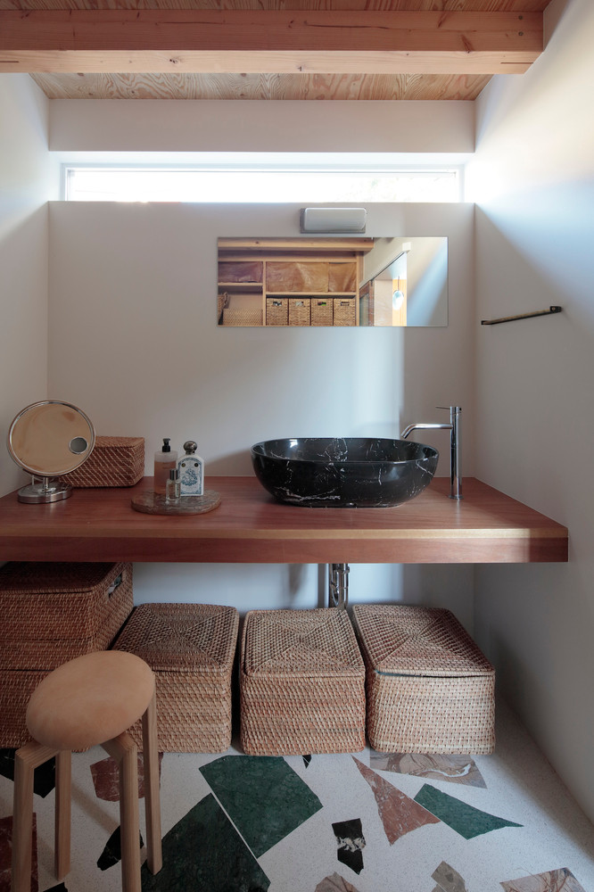 Từ hành lang bên này đi vào là phòng giặt đồ với những thùng đồ đan bằng mây được xếp gọn gàng, đồng màu với gam màu chủ đạo của ngôi nhà, tạo nên sự hài hòa về thẩm mỹ.