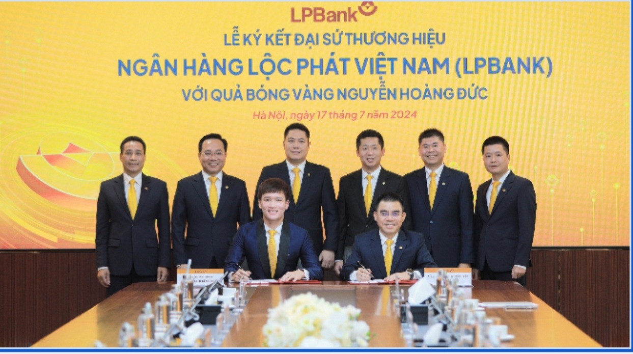 Quả bóng vàng Hoàng Đức (trái), ông Hồ Nam Tiến – Tổng Giám đốc LPBank (phải) ký Thỏa thuận Đại sứ thương hiệu dưới sự chứng kiến của Ban lãnh đạo Ngân hàng Lộc Phát Việt Nam.