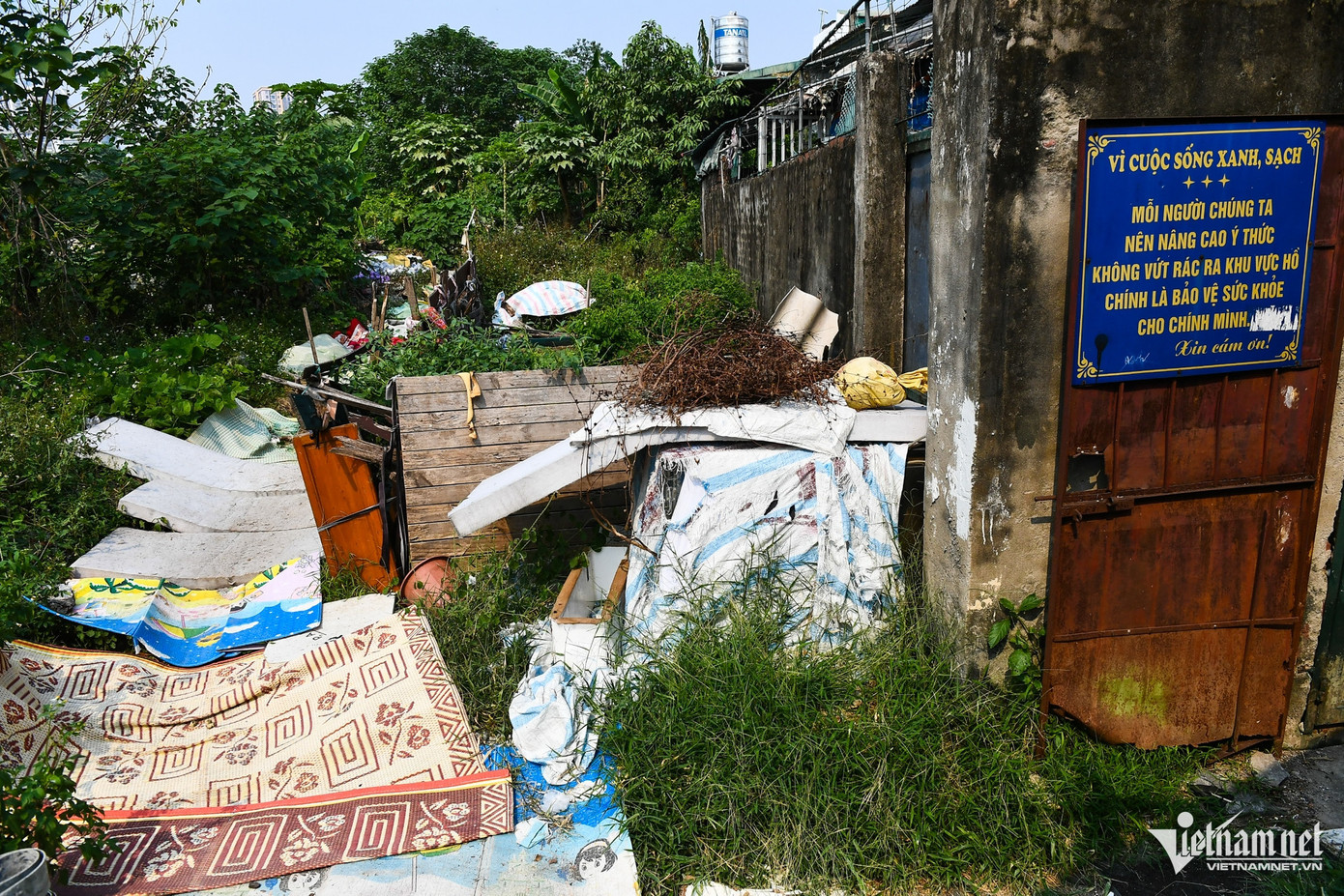 Ngay cạnh tấm biển cảnh báo không vứt rác bị ngập đầy phế liệu. Các tấm đệm, chiếu... bị vứt bỏ được sắp xếp cạnh nhau thành lối đi.