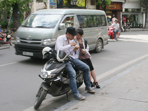 Đôi bạn trẻ thảnh nhiên dựng xe ăn kem dưới lề đường Lê Thái Tổ 
