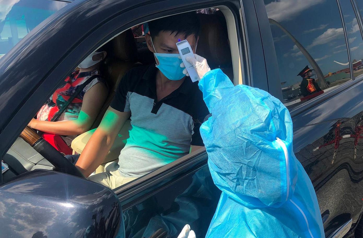 Nhân viên y tế đo thân nhiệt cho những người tham gia lưu thông bằng ô tô Nhân viên y tế đo thân nhiệt cho những người tham gia lưu thông bằng ô tô