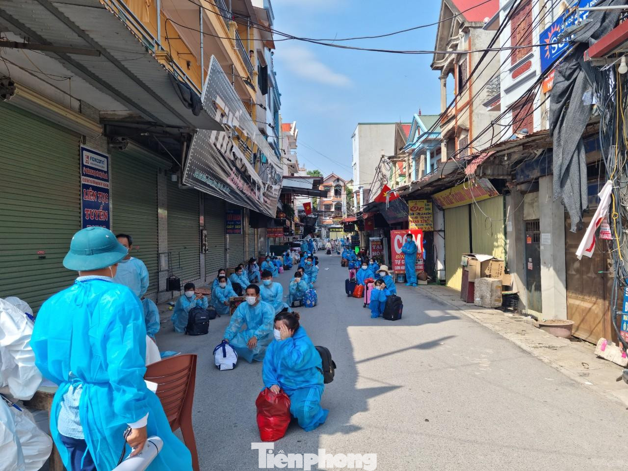 Công nhân xếp hàng, giãn cách để chuẩn bị lên xe ô tô di chuyển khỏi thôn Núi Hiểu. Công nhân xếp hàng, giãn cách để chuẩn bị lên xe ô tô di chuyển khỏi thôn Núi Hiểu.