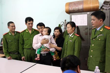 Cháu bé được các chiến sĩ công an trao trả cho gia đình. Ảnh: Báo HG