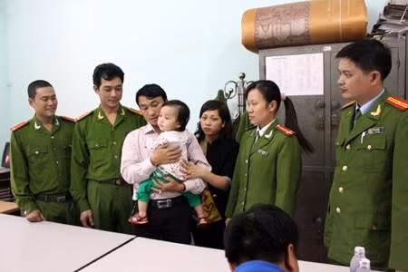 Cháu bé được các chiến sĩ công an trao trả cho gia đình. Ảnh: Báo HG