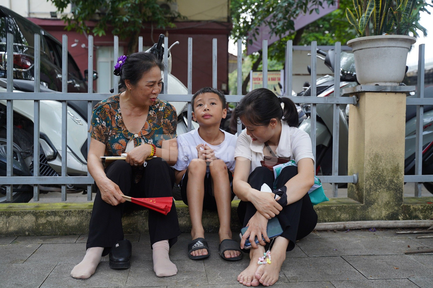 Bà Đoàn Thị Khu (người bên trái) ngồi đợi cháu gái thi cùng với cháu trai và con dâu. Bà Đoàn Thị Khu (người bên trái) ngồi đợi cháu gái thi cùng với cháu trai và con dâu.