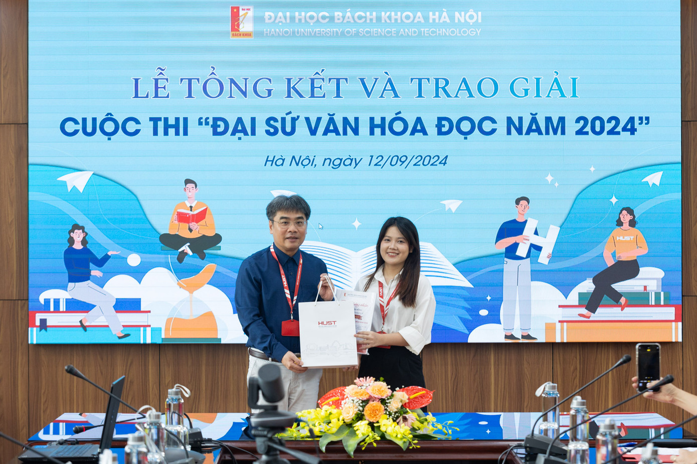 PGS.TS Huỳnh Đăng Chính, Phó Giám đốc Đại học Bách khoa Hà Nội trao phần thưởng cho đại sứ văn hóa đọc năm 2024 Lê Thị Thu Hồng (bên phải).