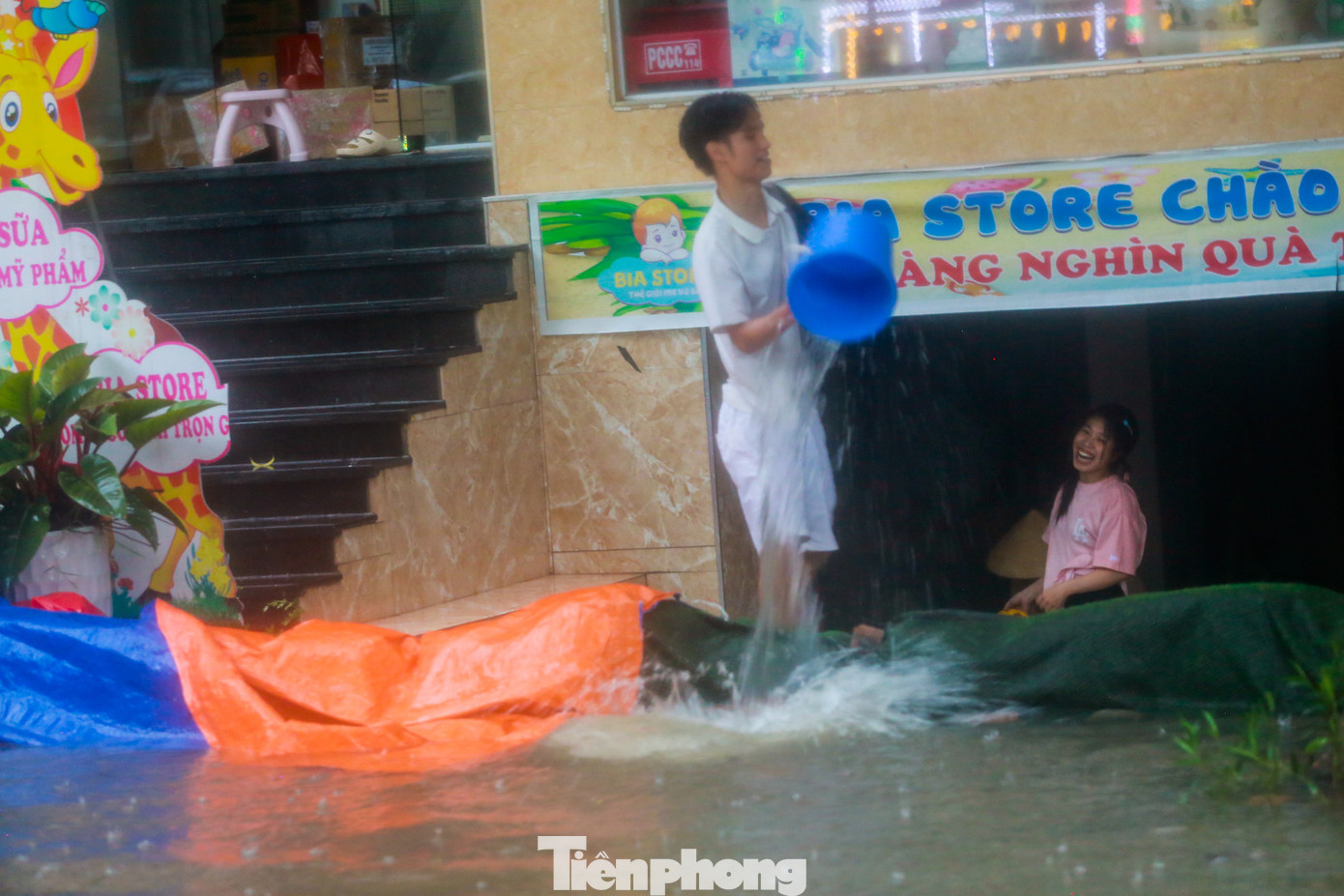 Người dân dùng xô tát nước sau khi nước tràn vào hầm.