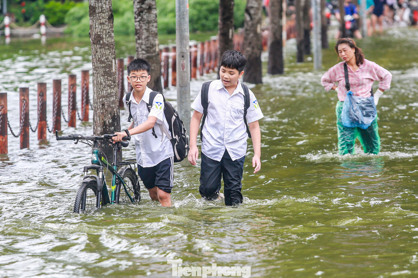 Học sinh dắt xe qua khu vực ngập úng.