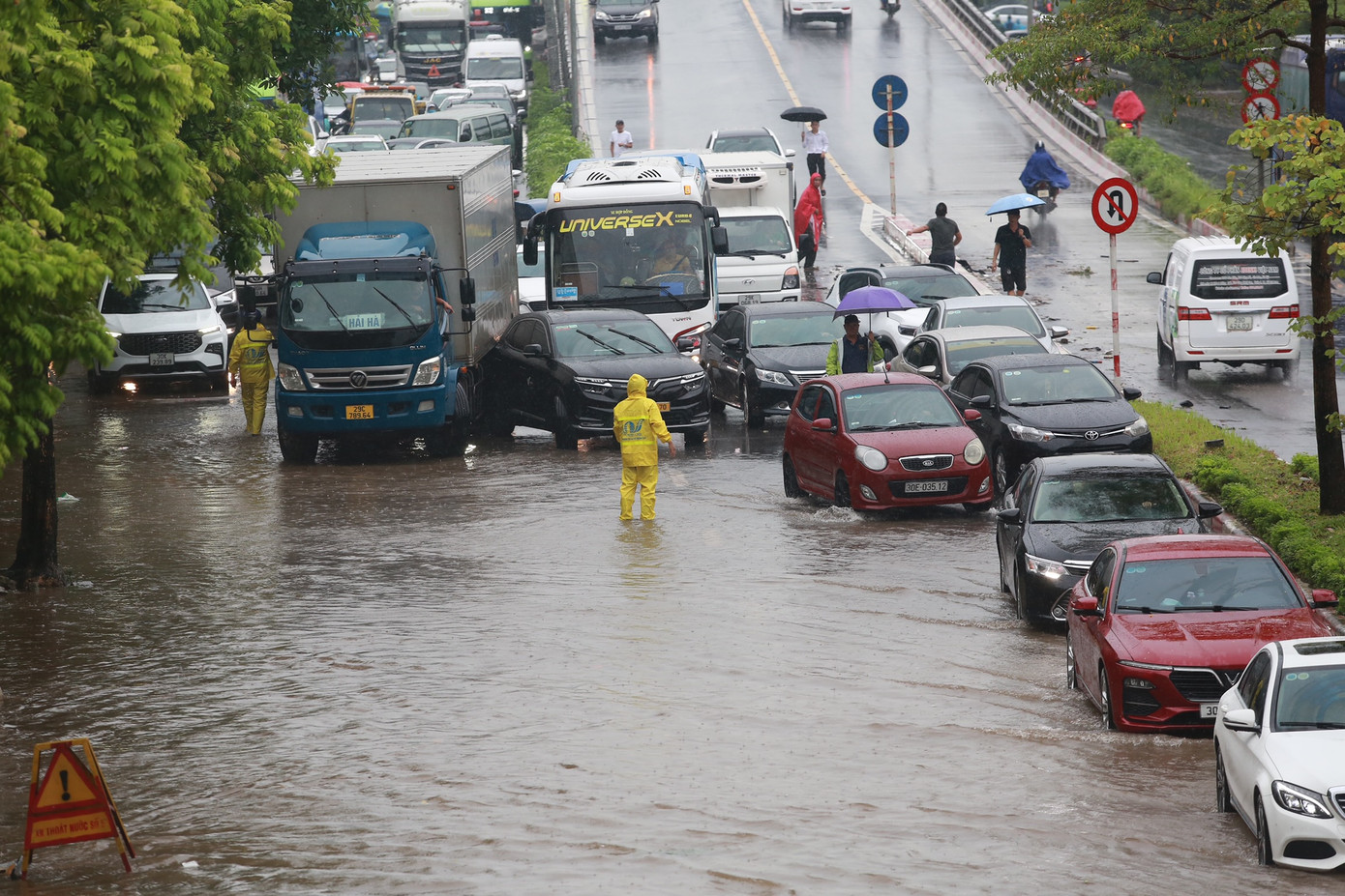 Đường Cổ Linh ngập sâu, các phương tiện ô tô chỉ có thể di chuyển thành một hàng cạnh dải phân cách.