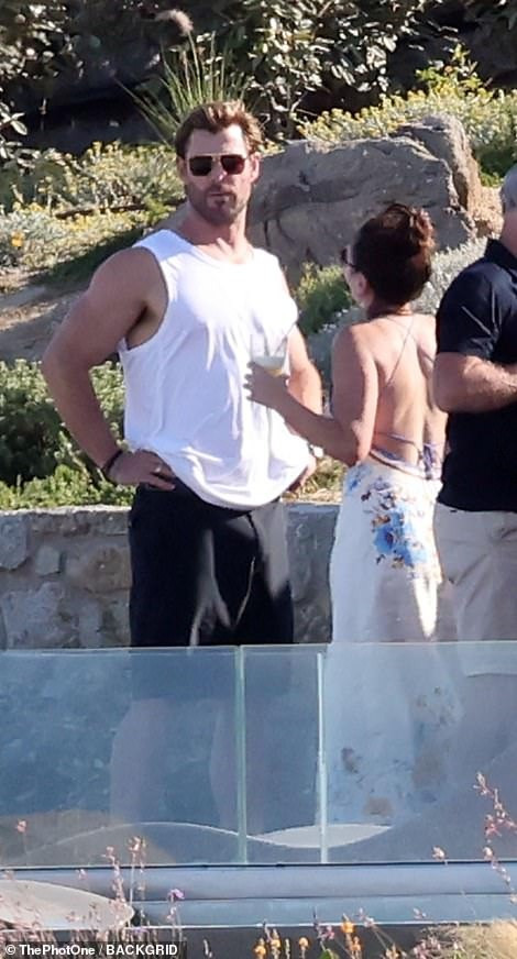 Trong kỳ nghỉ không có vợ ở bên, Chris trông thoải mái khi đứng giữa những phụ nữ diện bikini gợi cảm. Anh mặc áo ba lỗ và quần lửng màu đen khoe cơ bắp rắn rỏi.