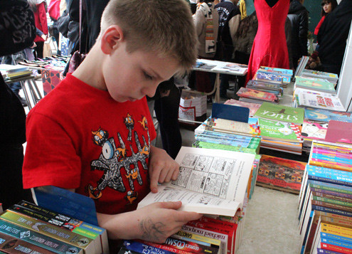 Cậu bé người nước ngoài say sưa đọc truyện trong một gian hàng