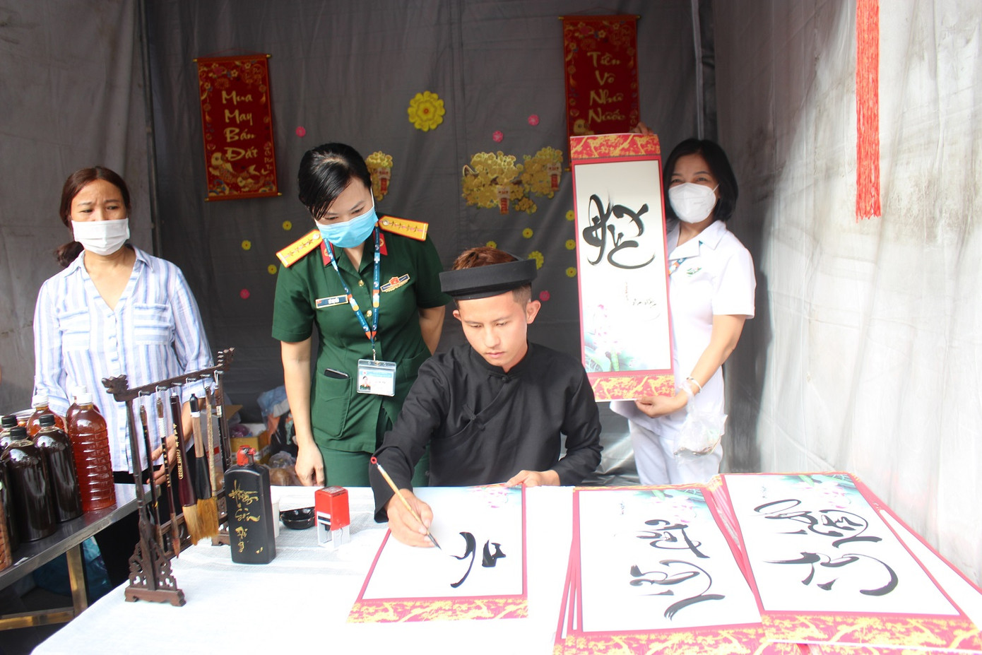 Nhiều người tranh thủ ghé gian hàng của ông đồ ngay trong phiên chợ để xin chữ nhân dịp Tết đến Xuân về Nhiều người tranh thủ ghé gian hàng của ông đồ ngay trong phiên chợ để xin chữ nhân dịp Tết đến Xuân về