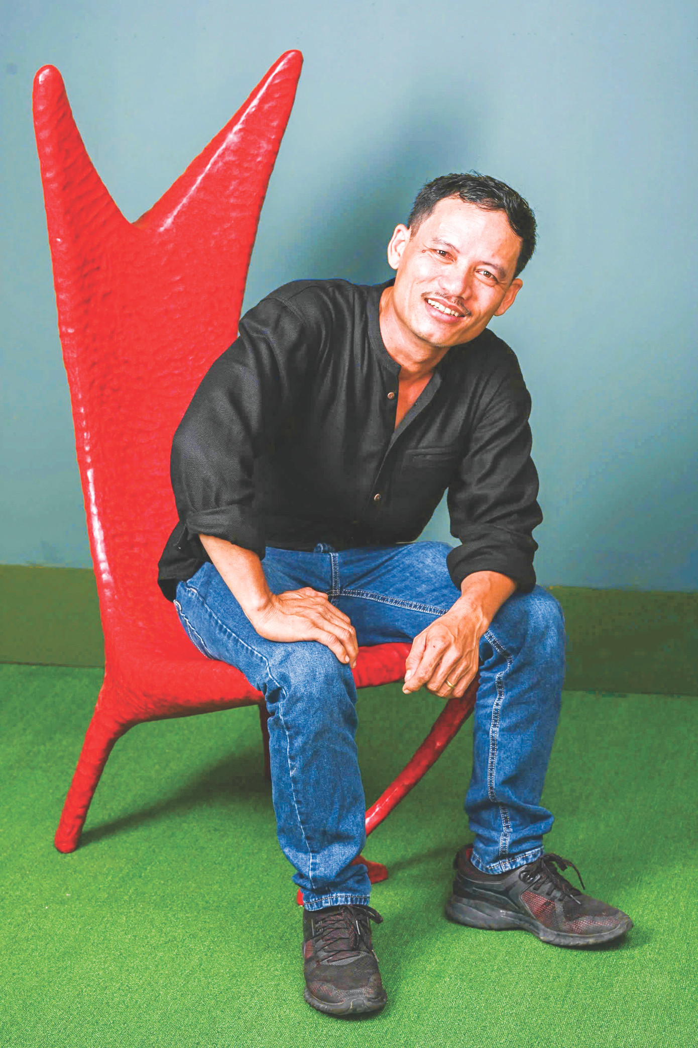 Họa sĩ Trần Thiện Nhứt bên cái ghế làm từ đồ tái chế rất được thị trường Mỹ ưa chuộng