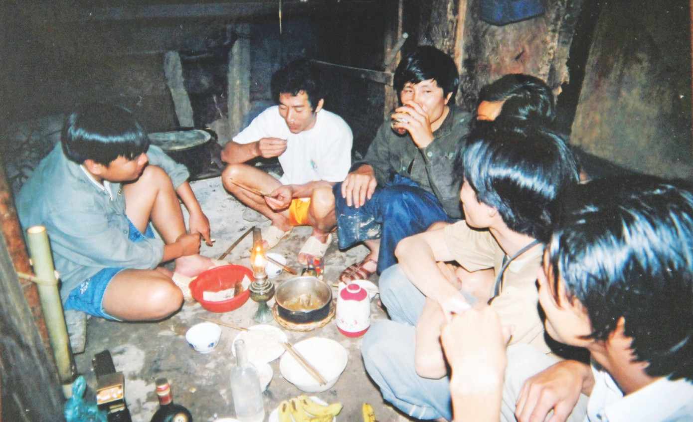 Tác giả (ngồi đối diện) giao lưu với thầy giáo hiệu trưởng, Anh hùng lao động Hà Công Văn (áo trắng, nay đã mất) tại gian bếp trường Tiểu học Húc Nghì (xã Húc Nghì, huyện Đăk Krông, Quảng Trị) trên đường xuyên Trường Sơn bằng xe máy, tháng 3/2022. Ảnh: Huỳnh Anh.