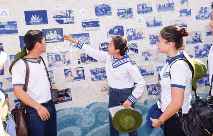 Họa sĩ Thu Thủy (giữa) bên những bức tranh gốm trong công viên Đại tướng Võ Nguyên Giáp tại đảo Sơn Ca. Ảnh: Nhân vật cung cấp.