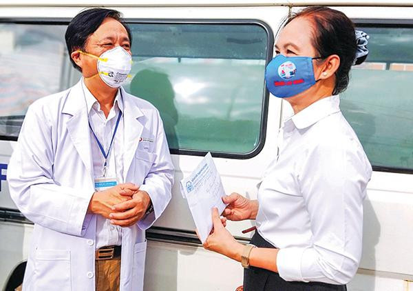Nhà văn Bích Ngân (phải) đại diện cho Hội Nhà văn TPHCM trao 100 triệu đồng quyên góp từ các nhà văn cho y bác sĩ Bệnh viện Đa khoa Thủ Đức. (Ảnh tư liệu)
