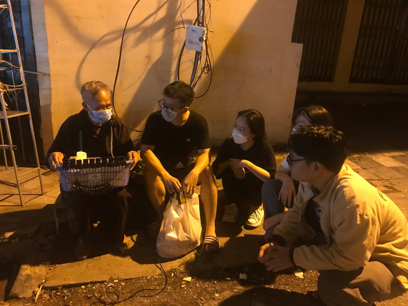 Các bạn tình nguyện của “Ấm” ngồi trò chuyện và thăm hỏi người vô gia cư