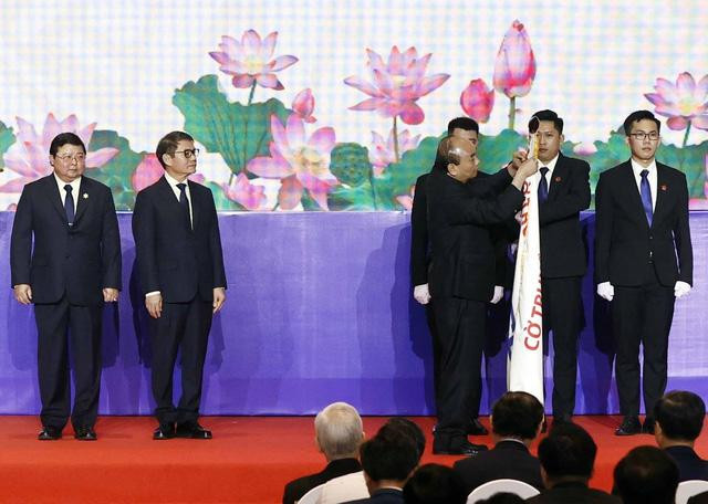 Chủ tịch nước Nguyễn Xuân Phúc gắn Huân chương Lao động hạng Nhất lên cờ truyền thống của THACO - Ảnh: TTXVN