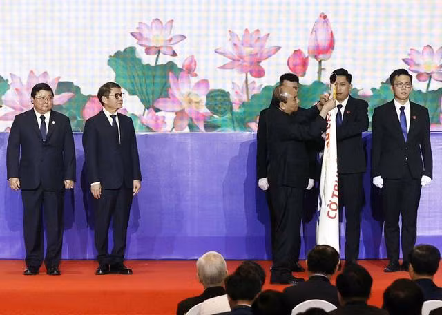 Chủ tịch nước Nguyễn Xuân Phúc gắn Huân chương Lao động hạng Nhất lên cờ truyền thống của THACO - Ảnh: TTXVN