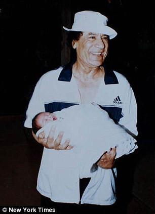 Ông Gaddafi tươi cười bế người con của mình. Ảnh: New York Times.
