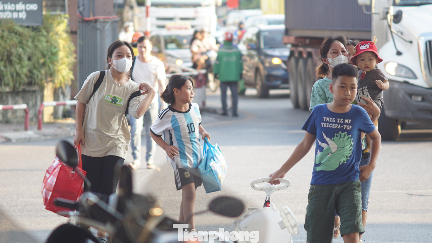 Nhiều gia đình có con nhỏ lỉnh kỉnh đồ đạc di chuyển trên đường.