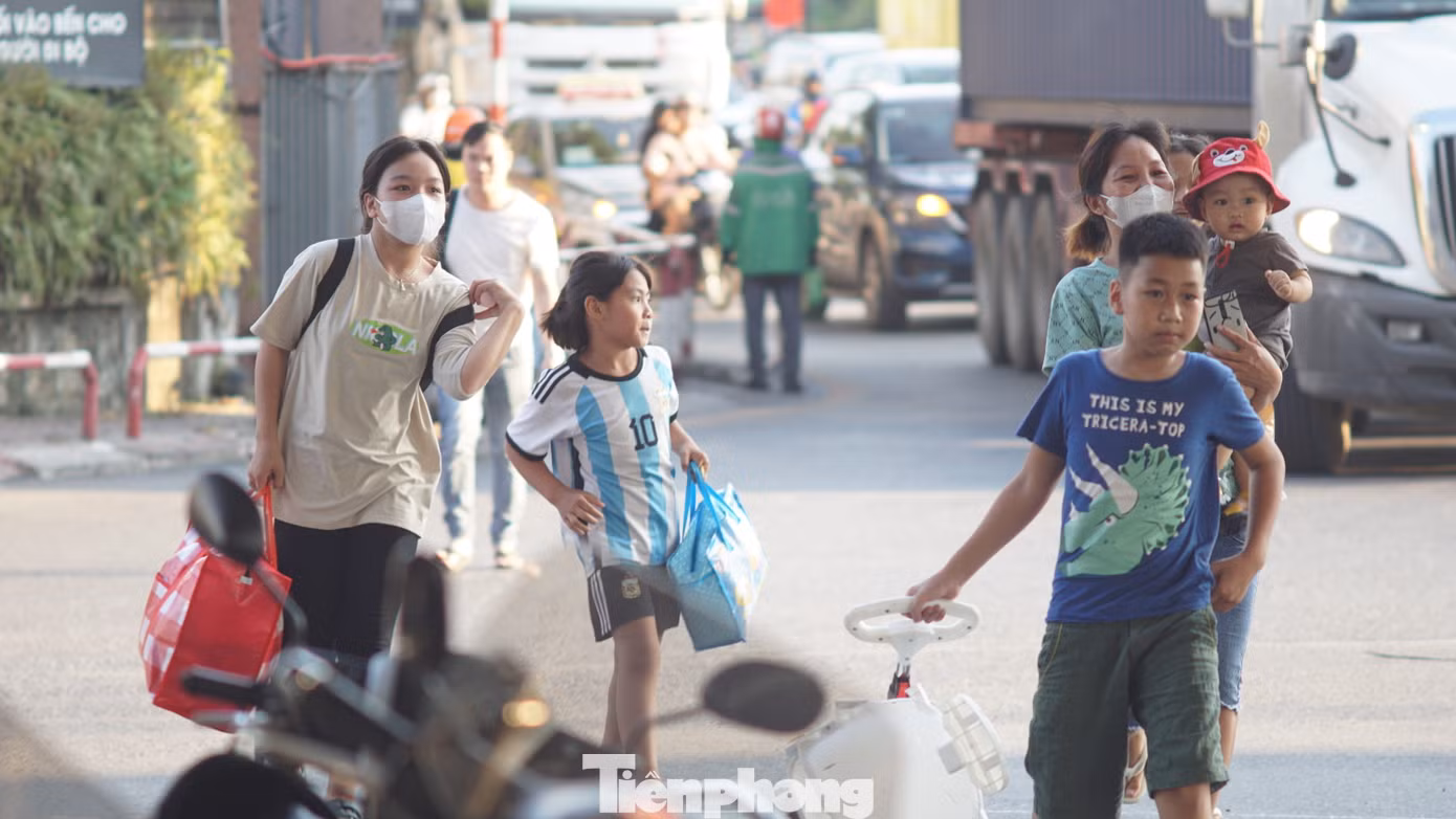 Nhiều gia đình có con nhỏ lỉnh kỉnh đồ đạc di chuyển trên đường.