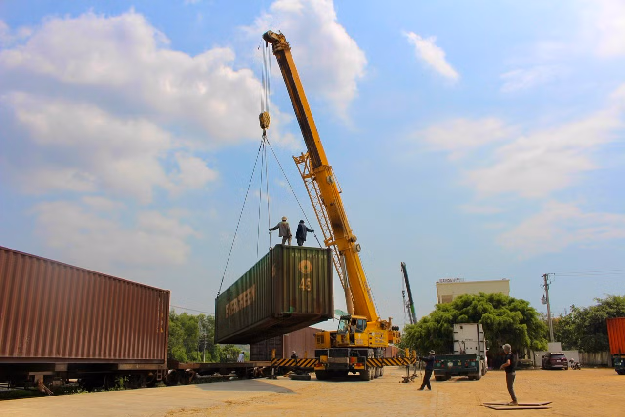 Dưới cái nắng gay gắt, các công nhân cùng cần cẩu liên tục bốc những container hàng từ tàu hỏa lên xe đầu kéo để trung chuyển.