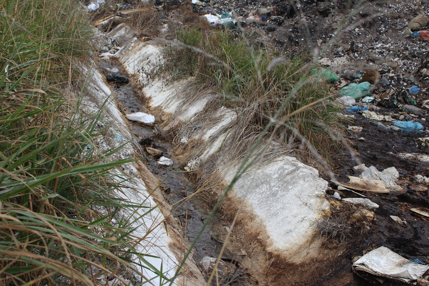 Dòng nước rỉ từ bãi rác đen ngòm, chảy thành dòng.