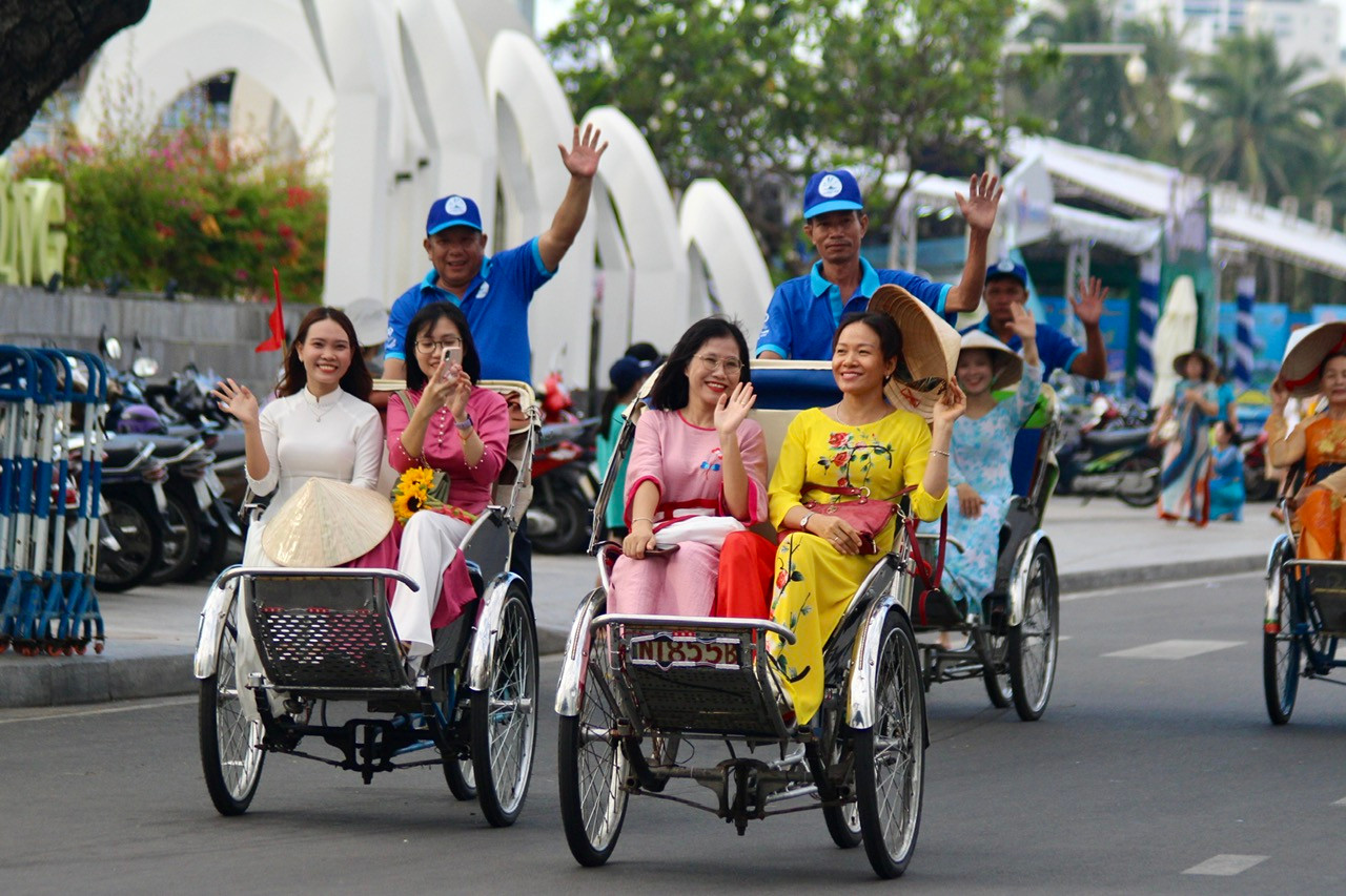 Trên mỗi chiếc xích lô đều được trang trí cờ và hoa. Những người phụ nữ trong tà áo dài tay cầm nón lá hoặc hoa vẫy chào người dân và du khách tạo nên một hình ảnh thật ấn tượng.