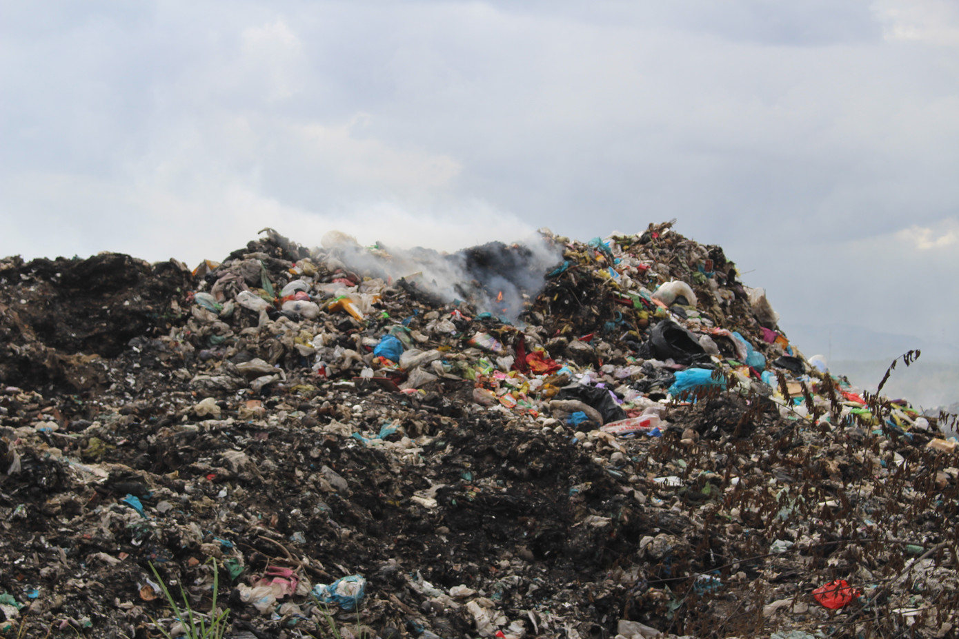 Rác cũ sau khi đốt được nén xuống thành từng tảng đen kịt, rác mới đổ tiếp tục được đốt.