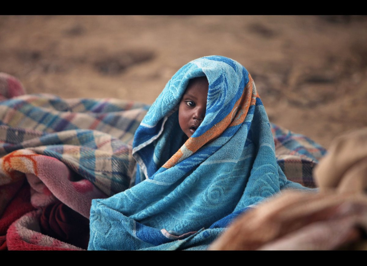 Em bé vô gia cư bọc mình trong chăn ở căn lều tạm dưới chân cầu vượt ở Jammu, Ấn Độ
