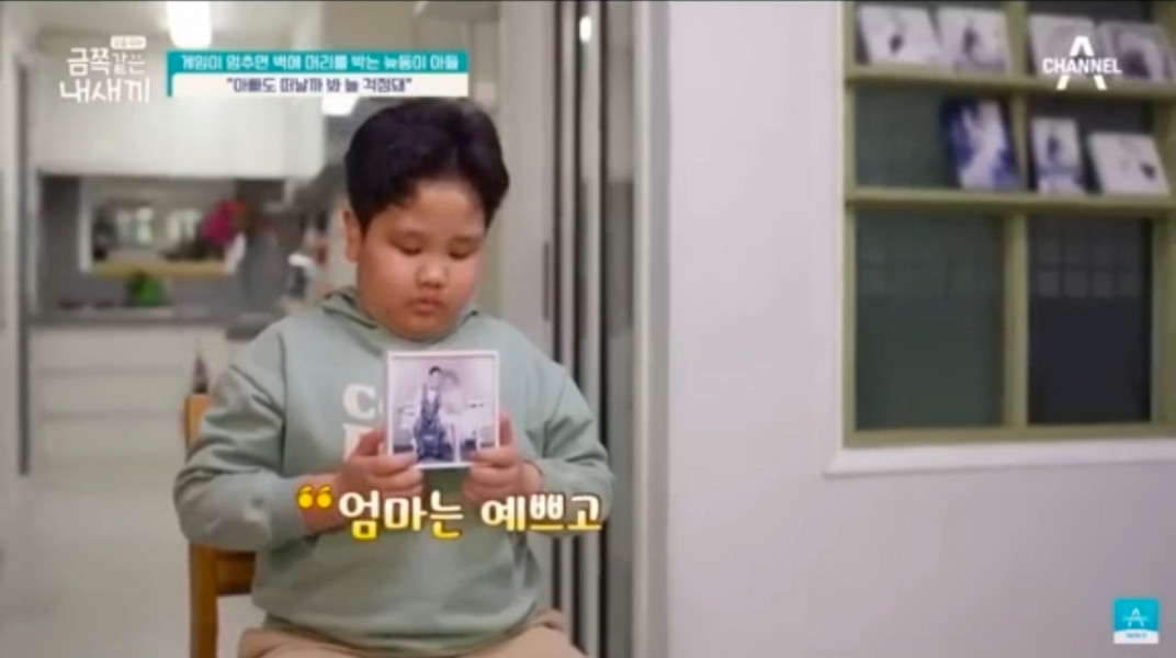 Cậu bé cầm lấy bức ảnh chụp của ba và mẹ, ngậm ngùi kể về người mẹ đã mất của mình. Cậu bé cầm lấy bức ảnh chụp của ba và mẹ, ngậm ngùi kể về người mẹ đã mất của mình.