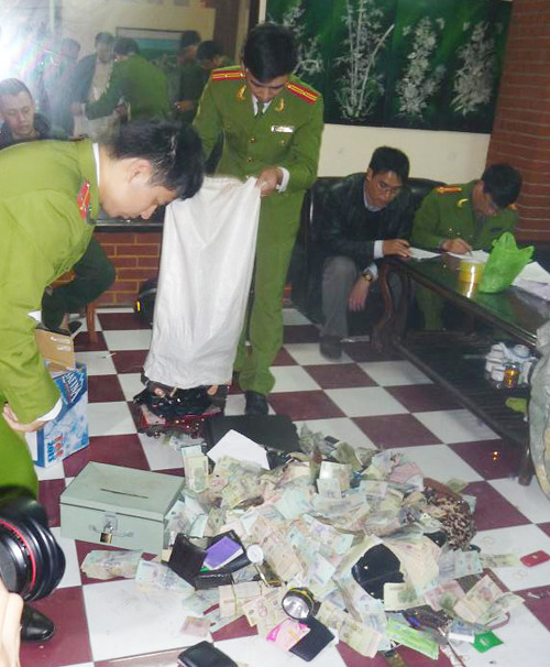 Những cô gái có mặt trong xới bạc. Các con bạc bị bắt. Cảnh sát kiểm tra số tiền.