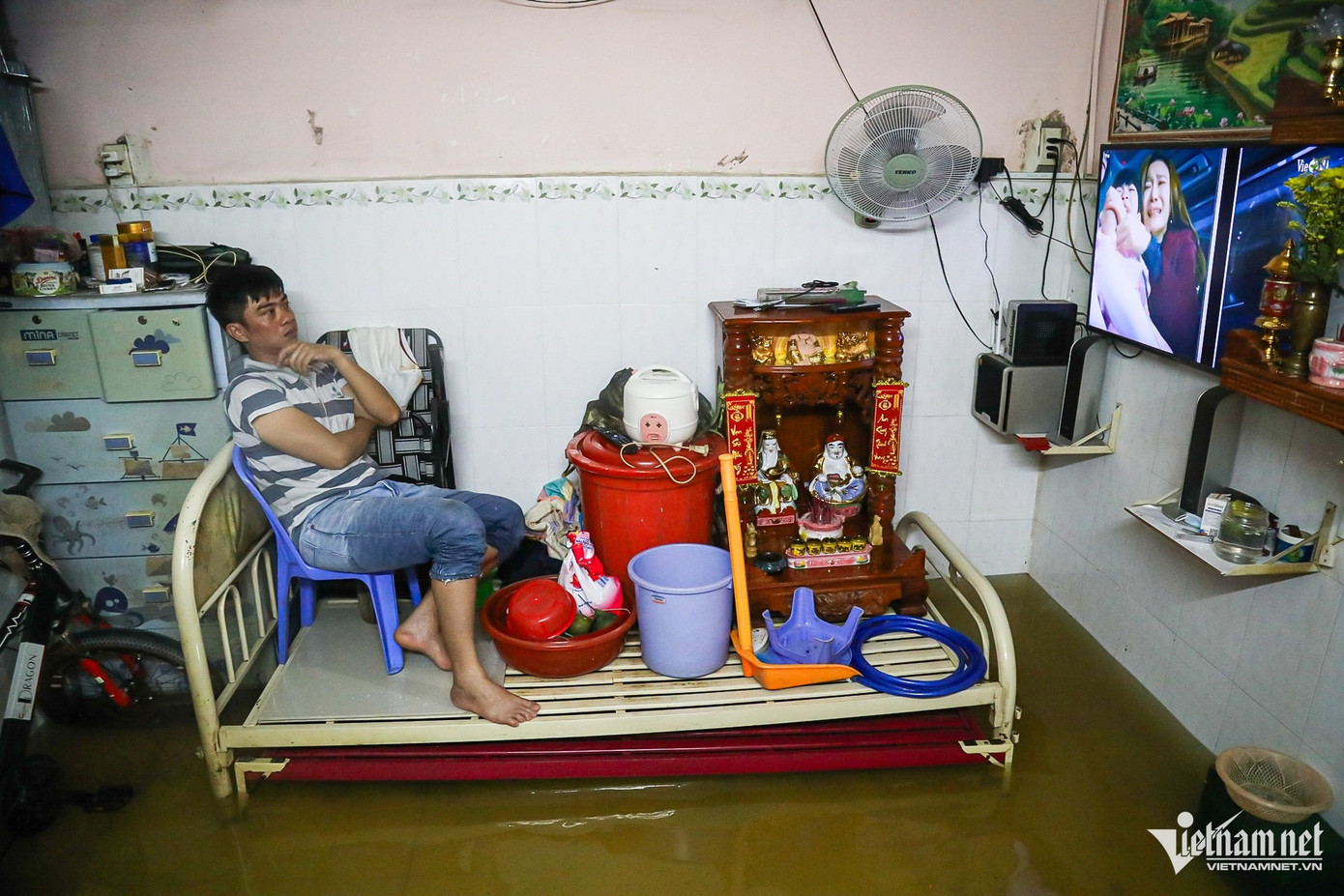 Anh Nghệ Thuật (hẻm 803 đường Huỳnh Tấn Phát) ngồi xem tivi trong lúc chờ nước rút. Đồ đạc trong nhà anh đã được bỏ hết lên giường. Nếu nước không rút, đêm nay anh không có chỗ ngủ. Anh Nghệ Thuật (hẻm 803 đường Huỳnh Tấn Phát) ngồi xem tivi trong lúc chờ nước rút. Đồ đạc trong nhà anh đã được bỏ hết lên giường. Nếu nước không rút, đêm nay anh không có chỗ ngủ.